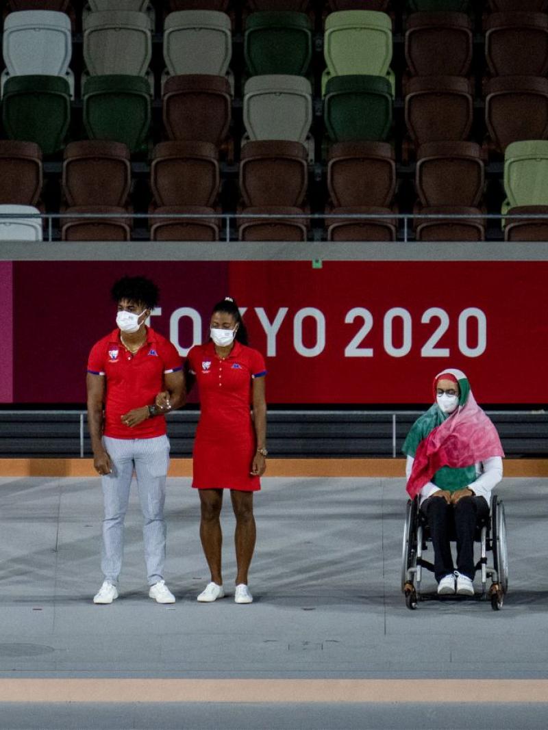 Four athletes and a guide wearing face masks are being presented. 