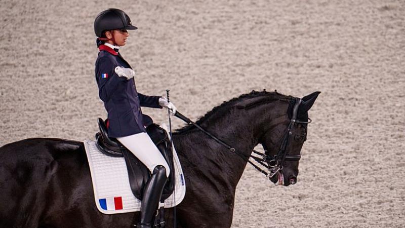 A female Para equestrian athlete rides a horse
