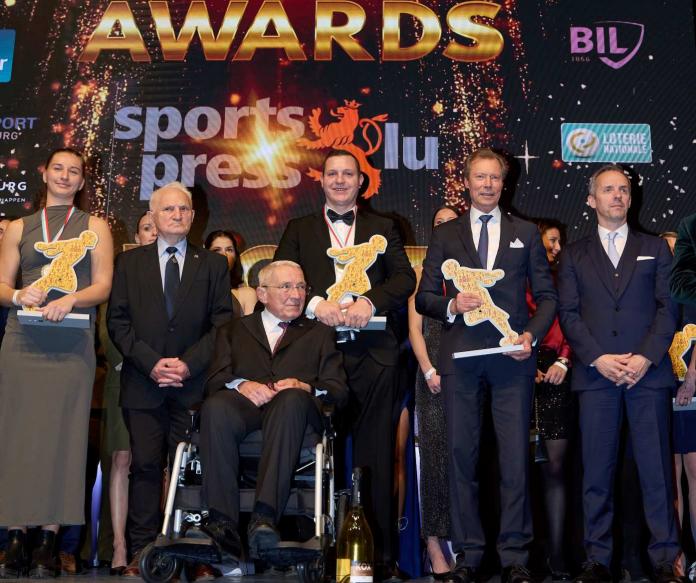 Six people holding trophies and posing for a photograph