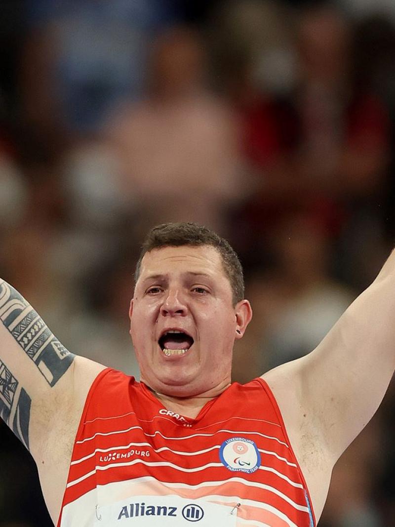 A male athlete opens his arms widely to celebrate