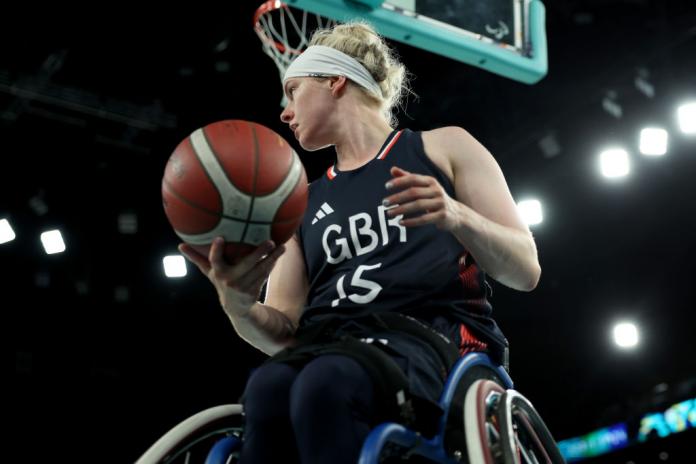 Robyn Love, a female wheelchair basketball player, looks to her right while holding a ball 