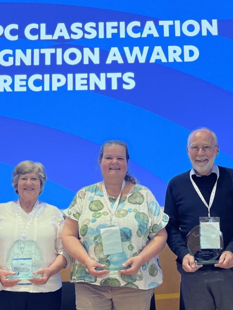 Five recipients pose for a photograph in front of a screen that says "2024 IPC Classification Recognition Awards Recipients"