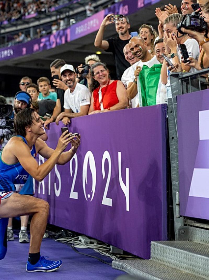 A man with a prosthetic leg kneeling to propose to his girlfriend in a packed stadium