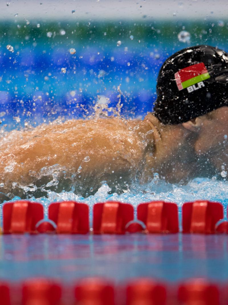 A man with a black cap swimming in a pool