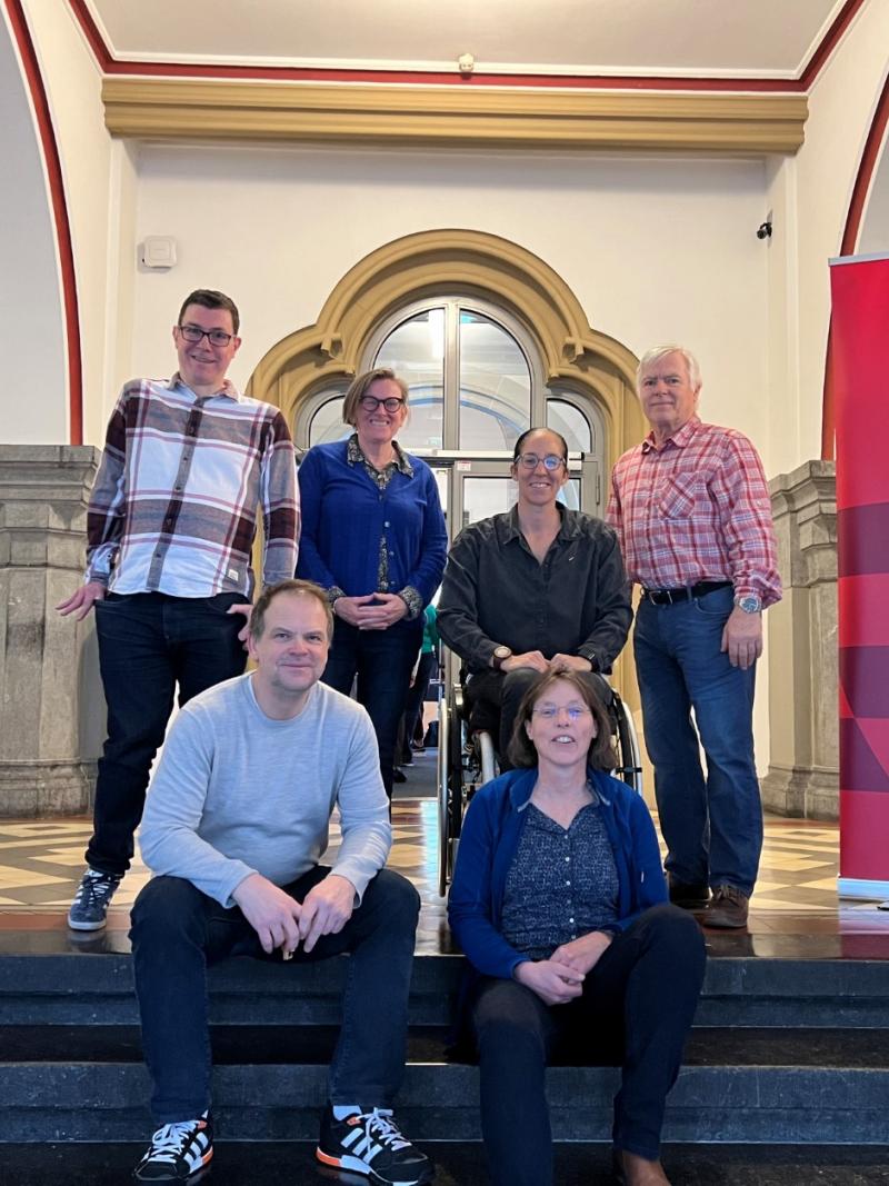 Six members of the Classification Compliance and Oversight Committee pose for a photo on the steps of an office building.