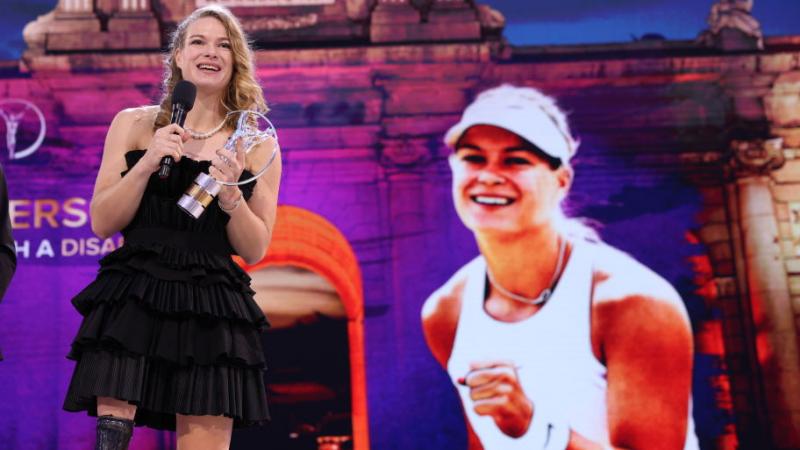 A female athlete makes a speech on a stage.