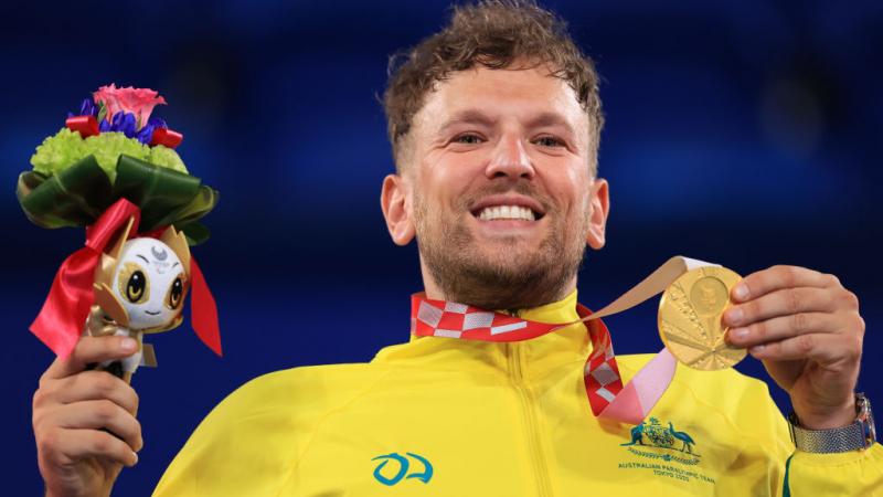 Dylan Alcott, a male wheelchair tennis player, poses for a photo with a gold medal.