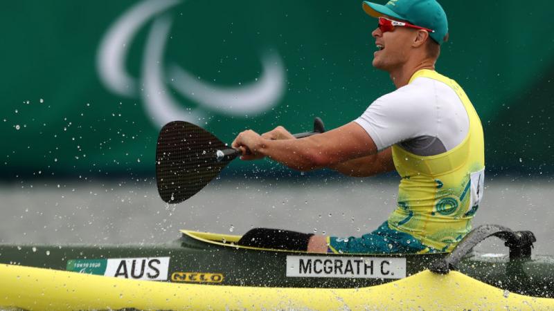 A man in a Team Australia uniform sits in a kayak and prepares to put his oar back in the water 