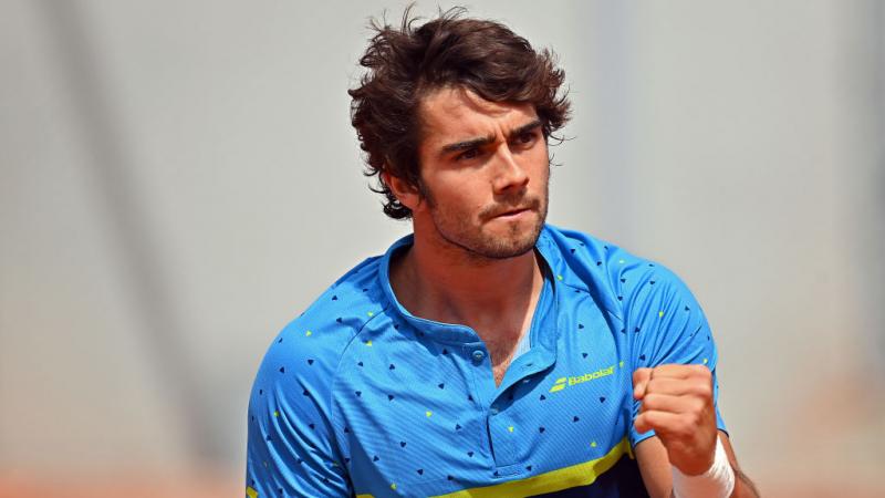 The Spanish wheelchair tennis player Daniel Caverzaschi, wearing a blue shirt, punches the air in celebration