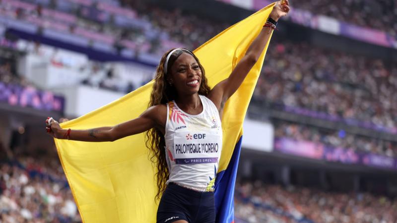 A female athlete with the Colombian flag in a stadium