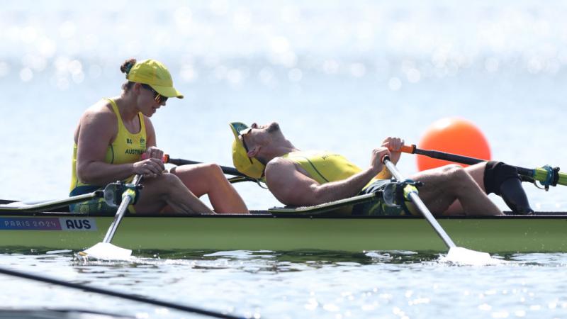 Two Australian rowers, dressed in yellow, look exhausted after winning gold in Paris