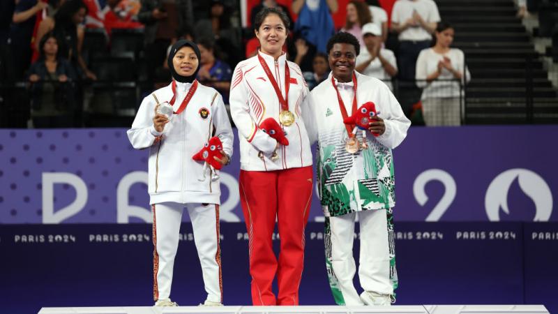 Three female Para badminton athletes with gold, silver and bronze medals on the podium