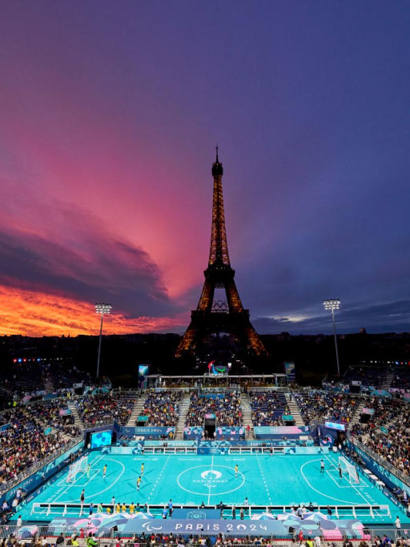 A view of the outdoor Paris 2024 blind football stadium at sunset, with the Eiffel Tower in the background