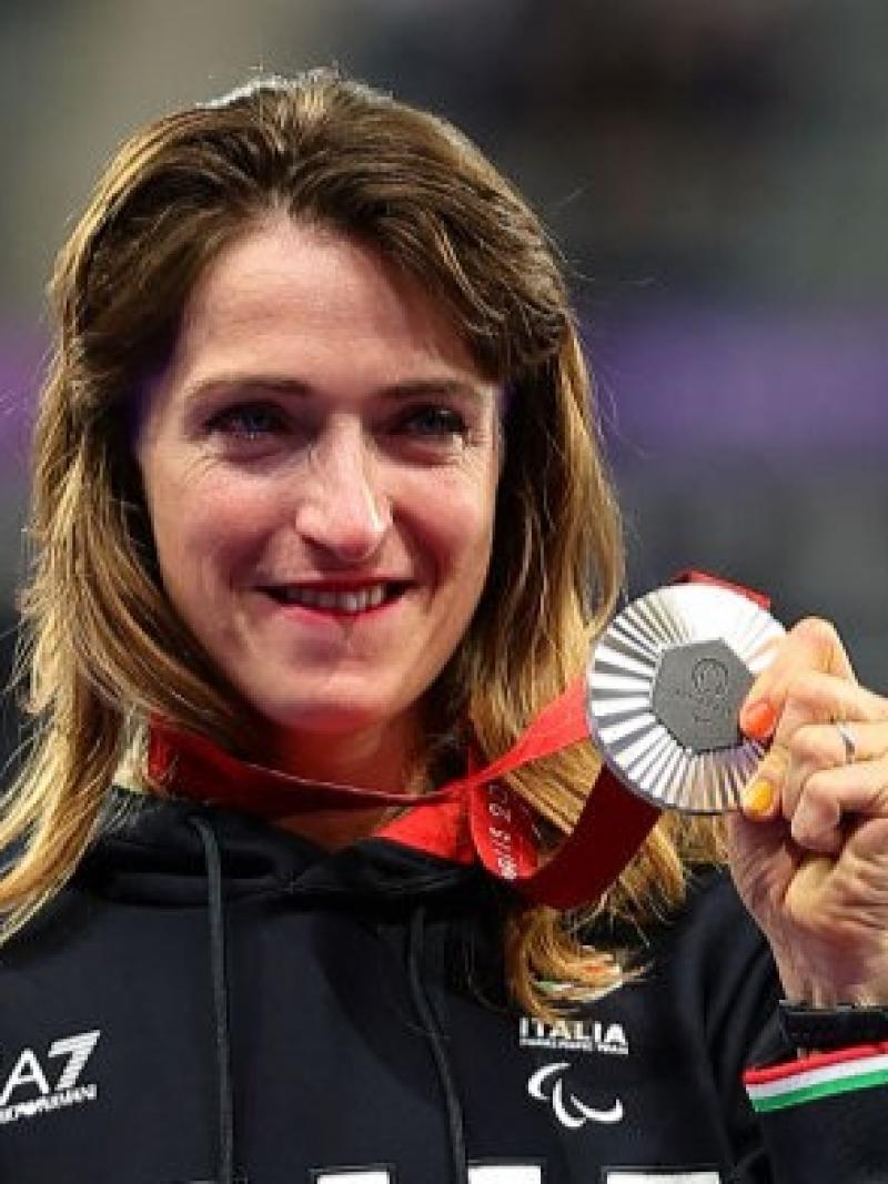 Para athlete Martina Caironi smiles and holds up a silver medal 