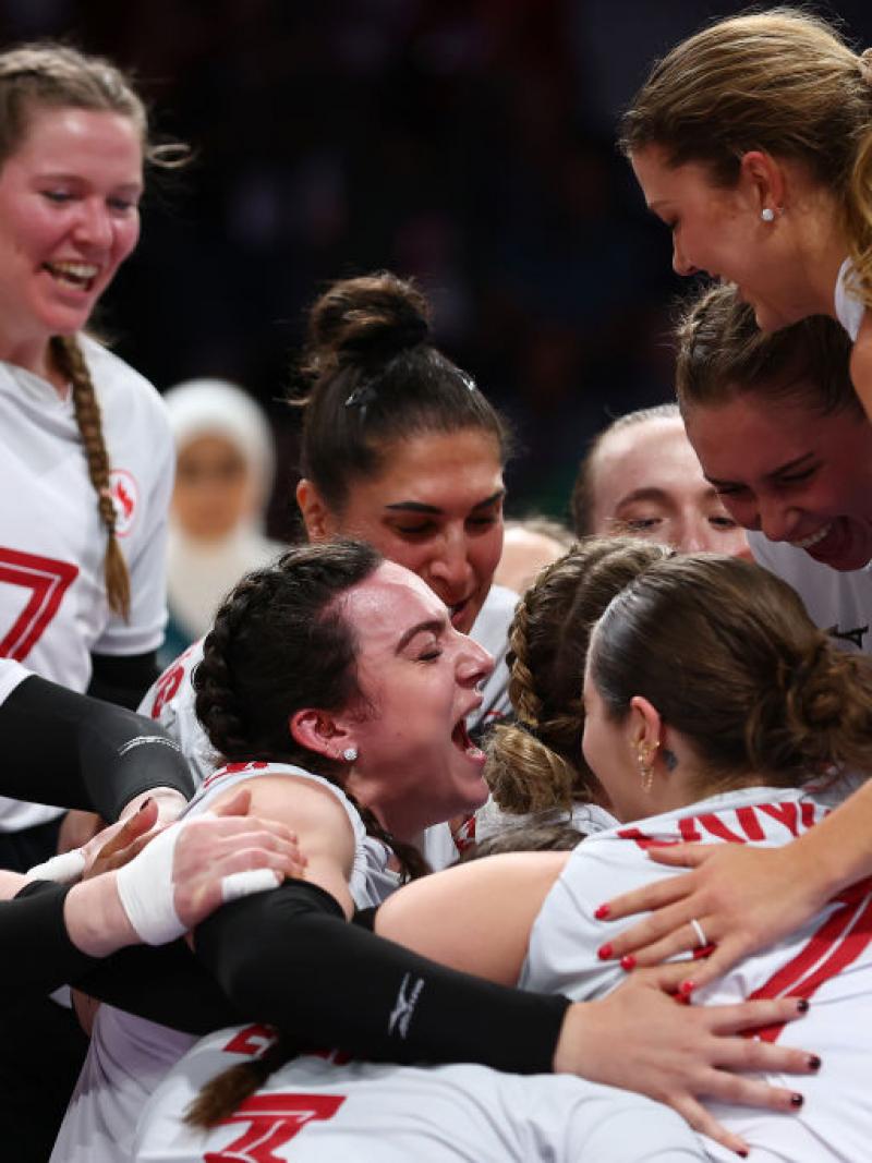 Canada's women's sitting volleyball team put their arms around each other and cheer in celebration