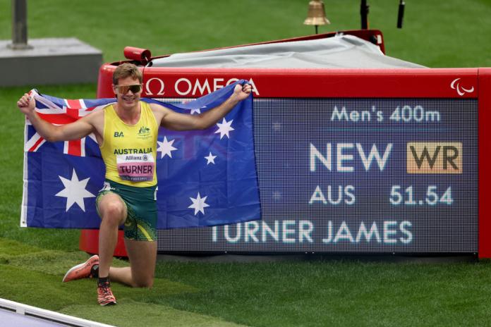 James Turner poses for a photo in front of the board that shows he broke the world record.