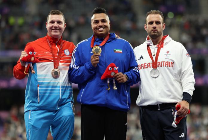 Three male athletes pose for photos with their medals 