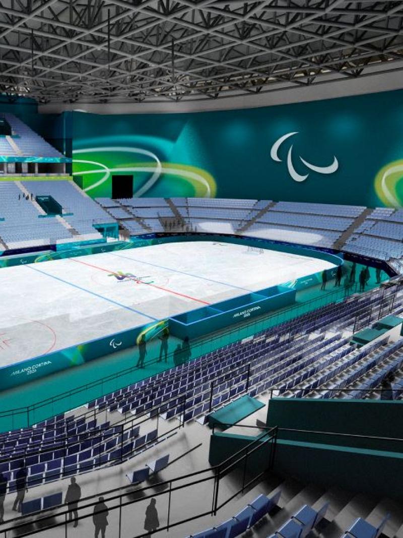 An image of a Para ice hockey rink. There are blue and green banners and signs