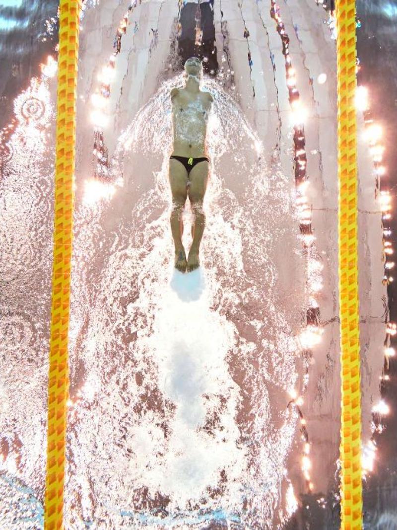 Three male athletes swim in a pool