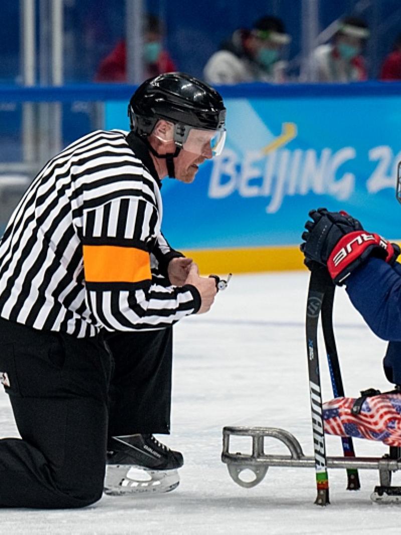 A Para ice hockey official and a player talking in an ice rink