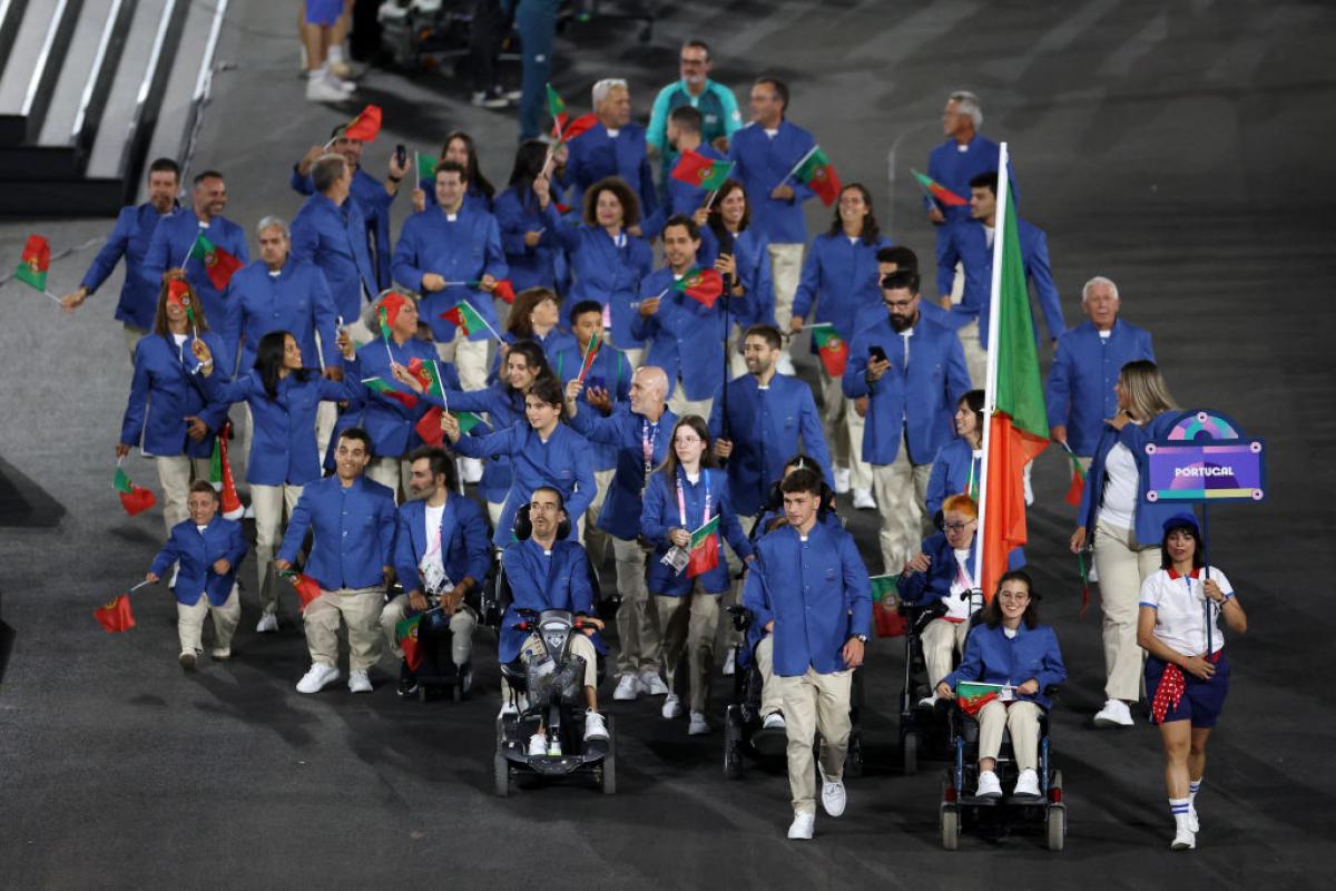 About 30 athletes take part in the parade of nations at the Paris 2024 Paralympic Opening Ceremony. They are all wearing a blue jacket and carries small flags of Portugal