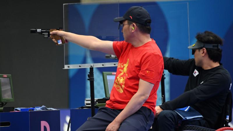Two male shooters in a pistol event in a shooting range