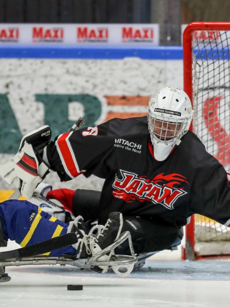 A Para ice hockey player taking a shot in front of the goaltender