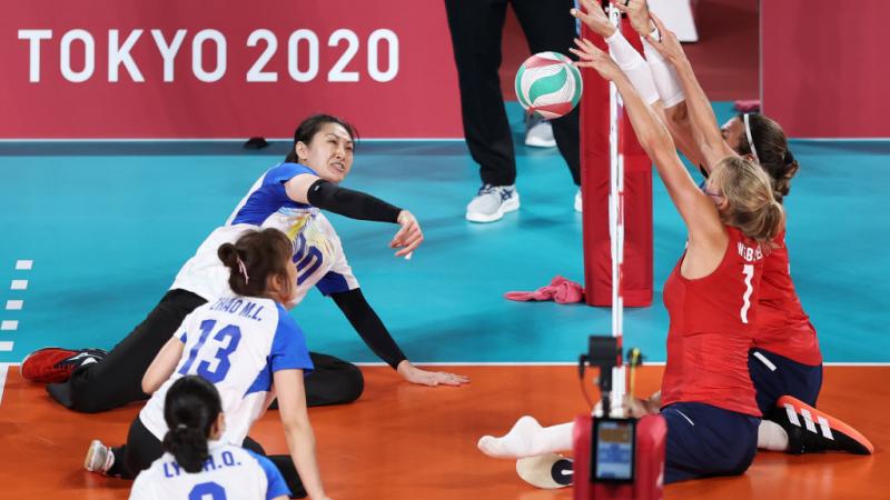 Yixiao Xu tries to get the ball over the net, while her opponent blocks.